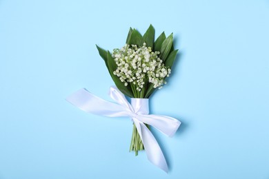 Photo of Beautiful lily-of-the-valley flowers on light blue background, top view
