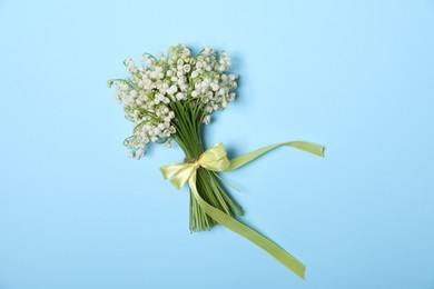Photo of Beautiful lily-of-the-valley flowers on light blue background, top view