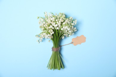 Photo of Beautiful lily-of-the-valley flowers on light blue background, top view