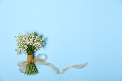 Photo of Beautiful lily-of-the-valley flowers on light blue background, top view. Space for text