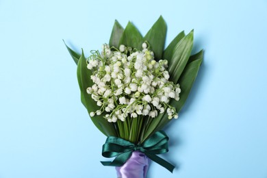 Photo of Beautiful lily-of-the-valley flowers on light blue background, top view