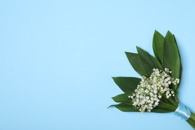 Photo of Beautiful lily-of-the-valley flowers on light blue background, top view. Space for text
