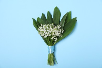 Photo of Beautiful lily-of-the-valley flowers on light blue background, top view