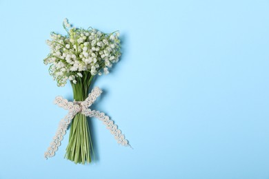 Photo of Beautiful lily-of-the-valley flowers on light blue background, top view. Space for text