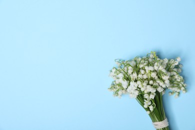 Photo of Beautiful lily-of-the-valley flowers on light blue background, top view. Space for text