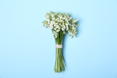 Photo of Beautiful lily-of-the-valley flowers on light blue background, top view