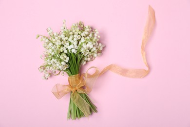 Photo of Beautiful lily-of-the-valley flowers on light pink background, top view