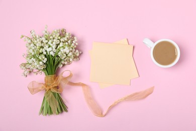 Photo of Beautiful lily-of-the-valley flowers, notes and coffee on light pink background, flat lay