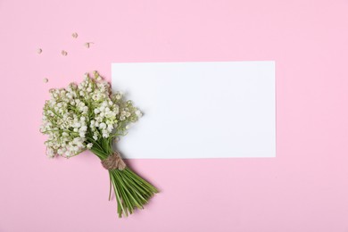 Photo of Beautiful lily-of-the-valley flowers and blank card on light pink background, top view. Space for text