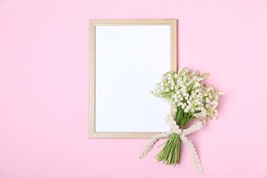 Photo of Beautiful lily-of-the-valley flowers and blank frame on light pink background, top view. Space for text