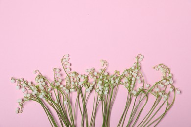 Photo of Beautiful lily-of-the-valley flowers on light pink background, flat lay. Space for text