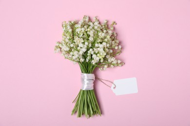 Photo of Beautiful lily-of-the-valley flowers on light pink background, top view