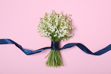 Photo of Beautiful lily-of-the-valley flowers on light pink background, top view