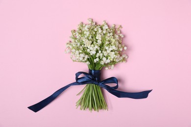 Photo of Beautiful lily-of-the-valley flowers on light pink background, top view