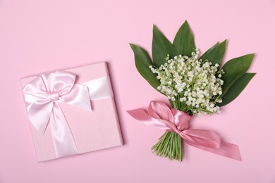 Photo of Beautiful lily-of-the-valley flowers and gift on light pink background, top view