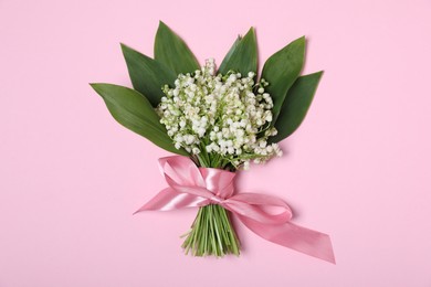 Photo of Beautiful lily-of-the-valley flowers on light pink background, top view