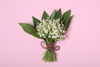 Photo of Beautiful lily-of-the-valley flowers on light pink background, top view