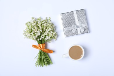 Photo of Beautiful lily-of-the-valley flowers, coffee and gift on white background, flat lay