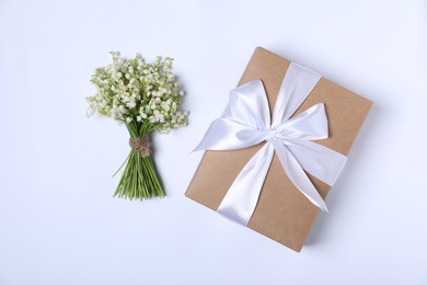Photo of Beautiful lily-of-the-valley flowers and gift on white background, flat lay