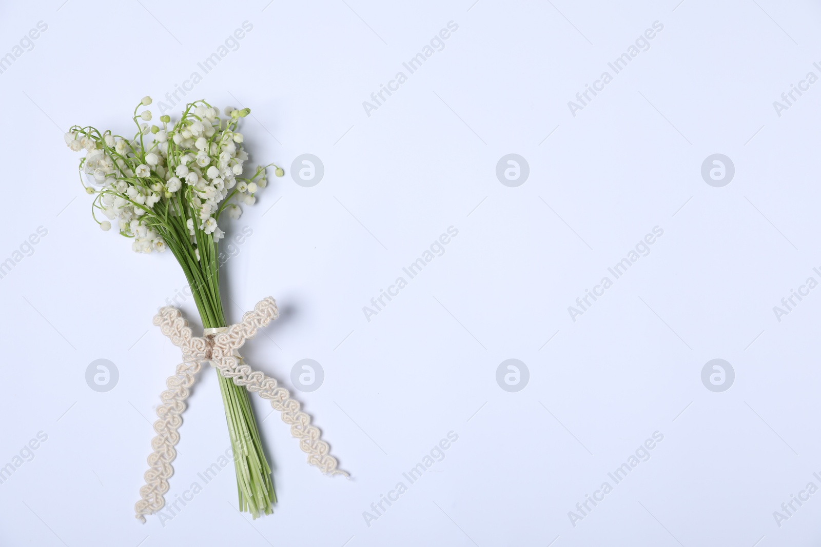 Beautiful lily-of-the-valley flowers on white background, top view. Space for text Photo of Beautiful lily-of-the-valley flowers on white background, top view. Space for text