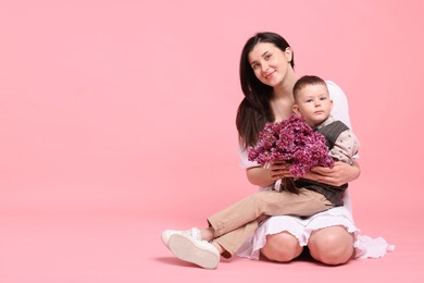 Photo of Mother and her son with bouquet of lilac flowers on pink background, space for text