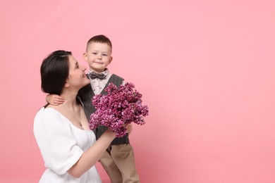Photo of Mother and her son with bouquet of lilac flowers on pink background, space for text