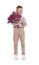 Photo of Little boy with bouquet of lilac flowers on white background