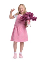 Photo of Little girl with bouquet of lilac flowers showing V-sign on white background