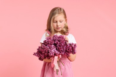 Photo of Little girl with bouquet of lilac flowers on pink background