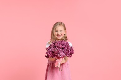 Photo of Little girl with bouquet of lilac flowers on pink background