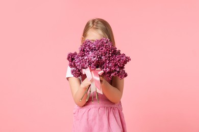 Photo of Little girl with bouquet of lilac flowers on pink background