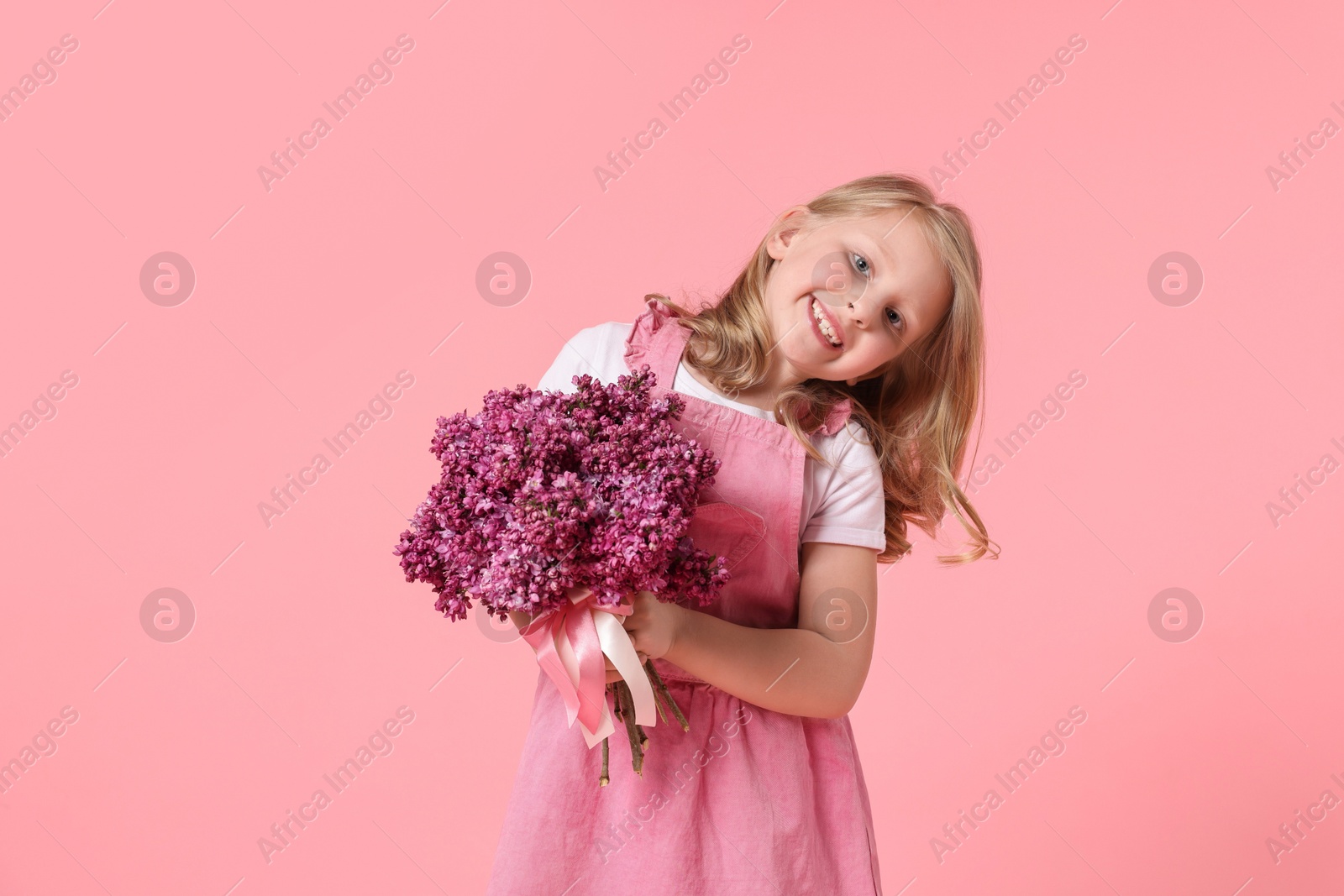 Little girl with bouquet of lilac flowers on pink background Photo of Little girl with bouquet of lilac flowers on pink background
