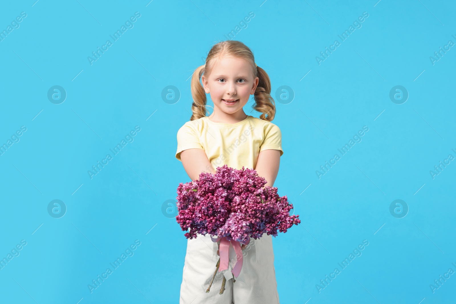 Little girl with bouquet of lilac flowers on light blue background Photo of Little girl with bouquet of lilac flowers on light blue background