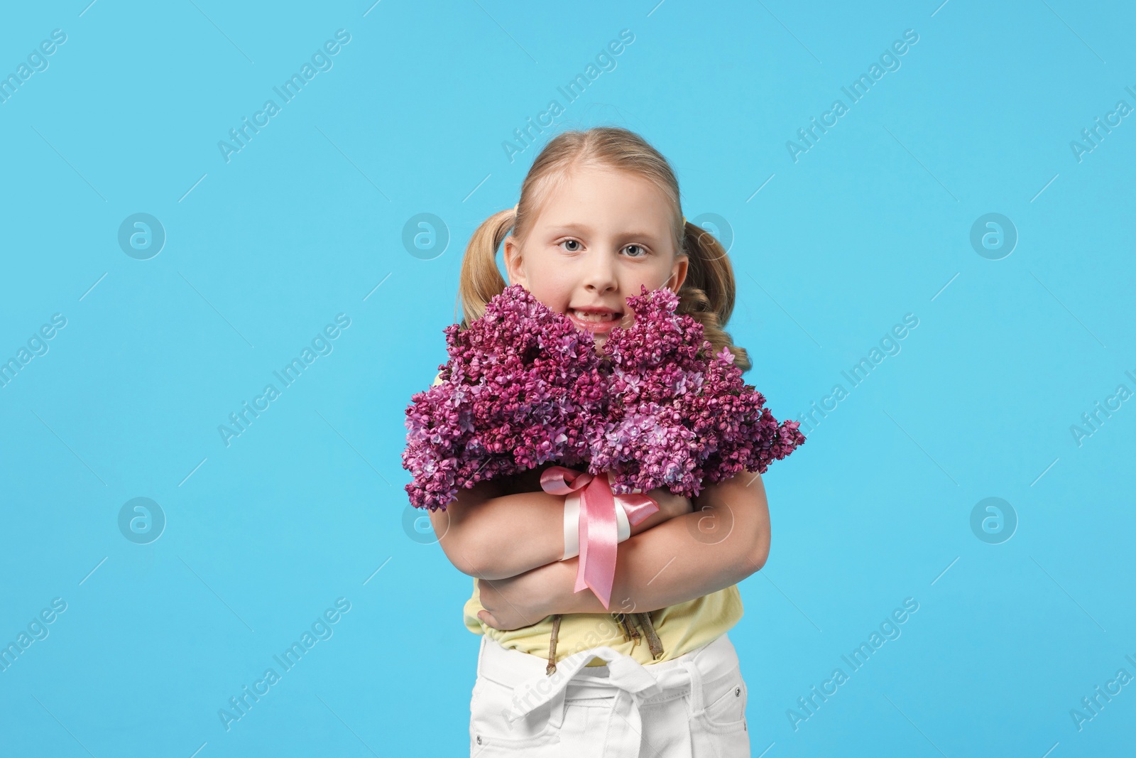 Little girl with bouquet of lilac flowers on light blue background Photo of Little girl with bouquet of lilac flowers on light blue background