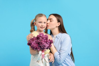 Photo of Mother and her daughter with bouquet of lilac flowers on light blue background