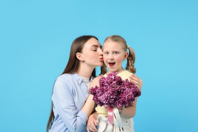 Photo of Mother and her daughter with bouquet of lilac flowers on light blue background
