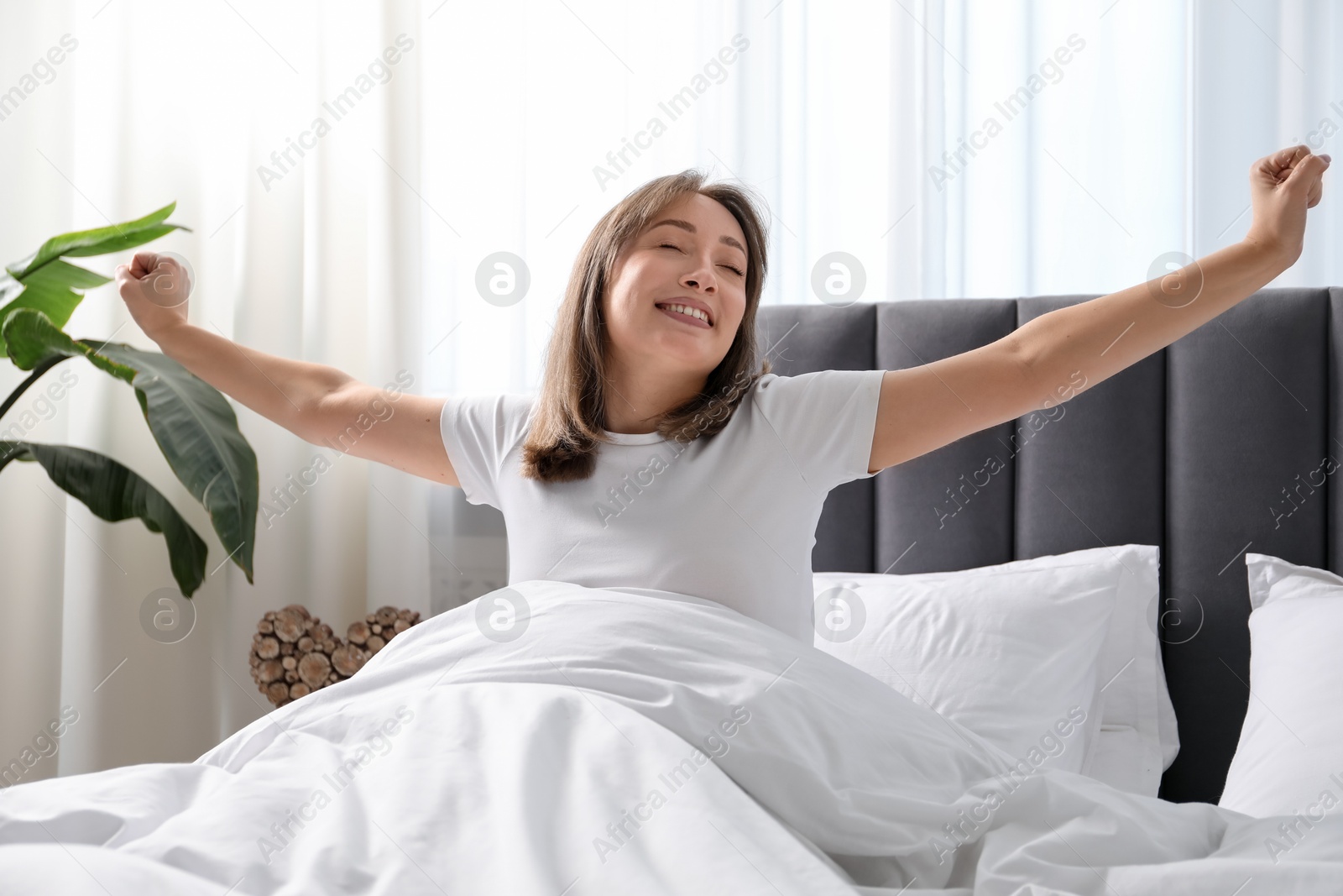 Beautiful woman stretching in bed at home Photo of Beautiful woman stretching in bed at home