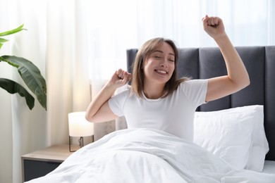 Photo of Beautiful woman stretching in bed at home