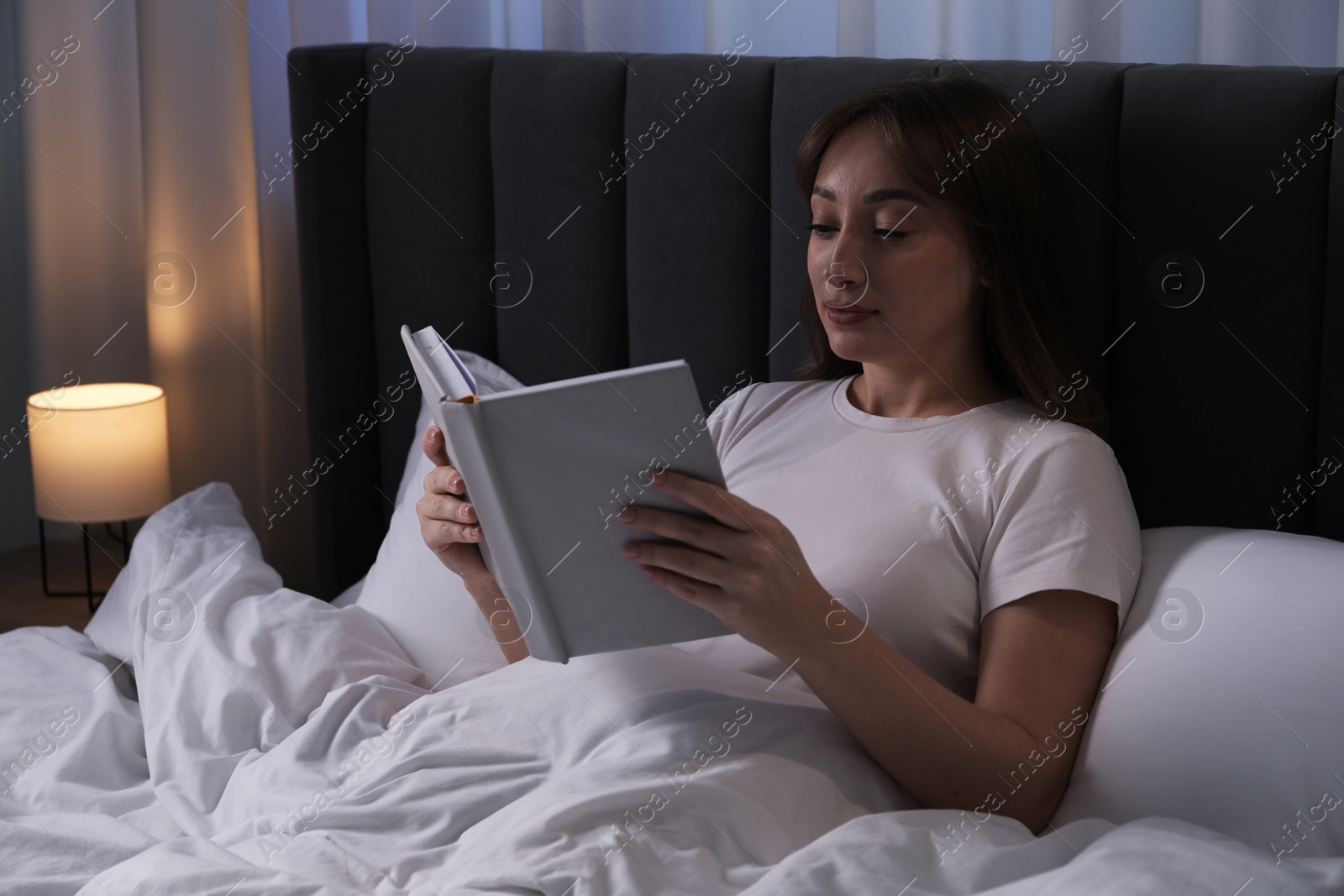 Beautiful woman reading book in bed at home Photo of Beautiful woman reading book in bed at home
