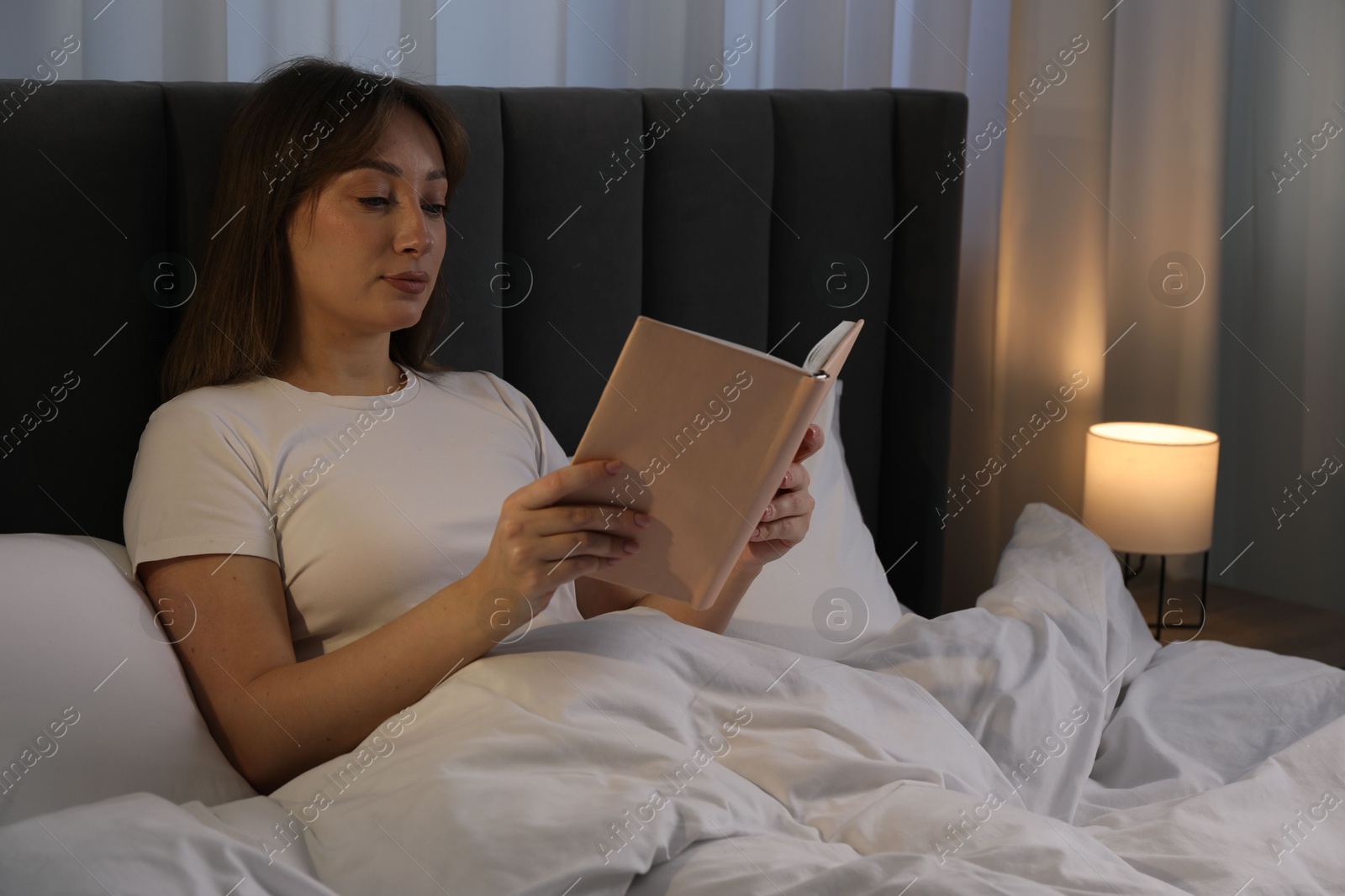 Beautiful woman reading book in bed at home Photo of Beautiful woman reading book in bed at home