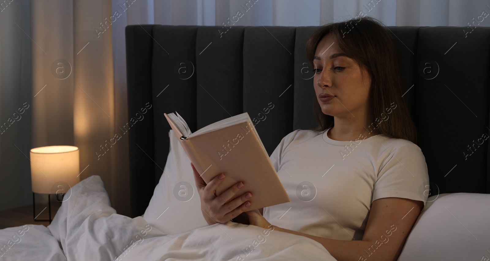 Beautiful woman reading book in bed at home Photo of Beautiful woman reading book in bed at home