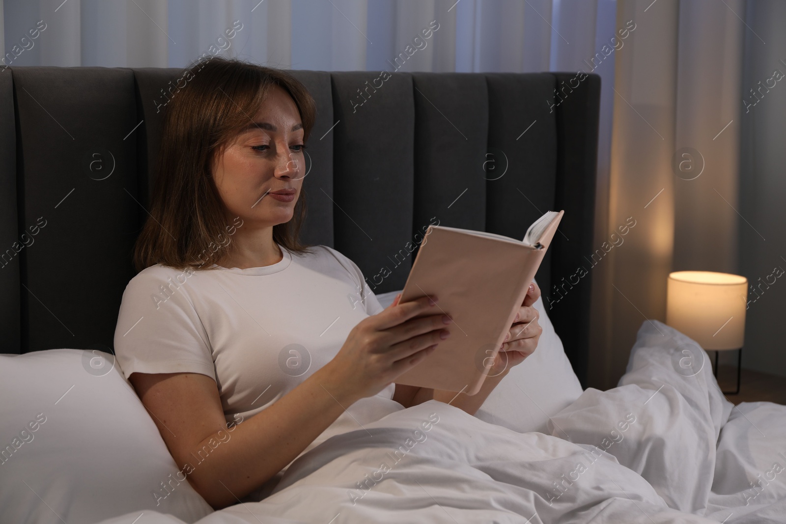 Beautiful woman reading book in bed at home Photo of Beautiful woman reading book in bed at home