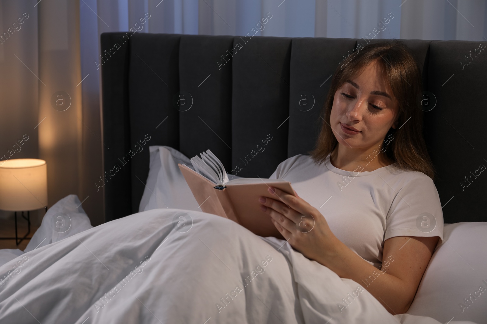 Beautiful woman reading book in bed at home Photo of Beautiful woman reading book in bed at home