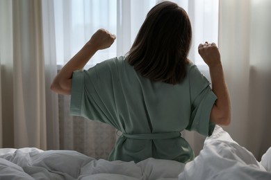 Photo of Woman stretching in bed at home, back view