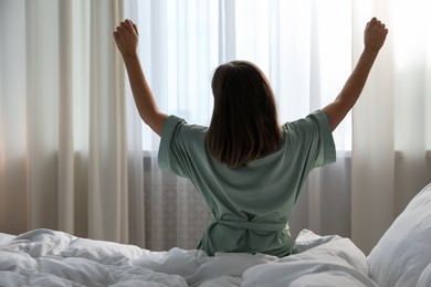 Photo of Woman stretching in bed at home, back view