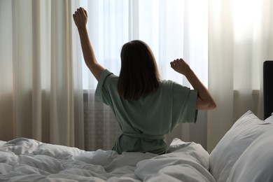 Photo of Woman stretching in bed at home, back view