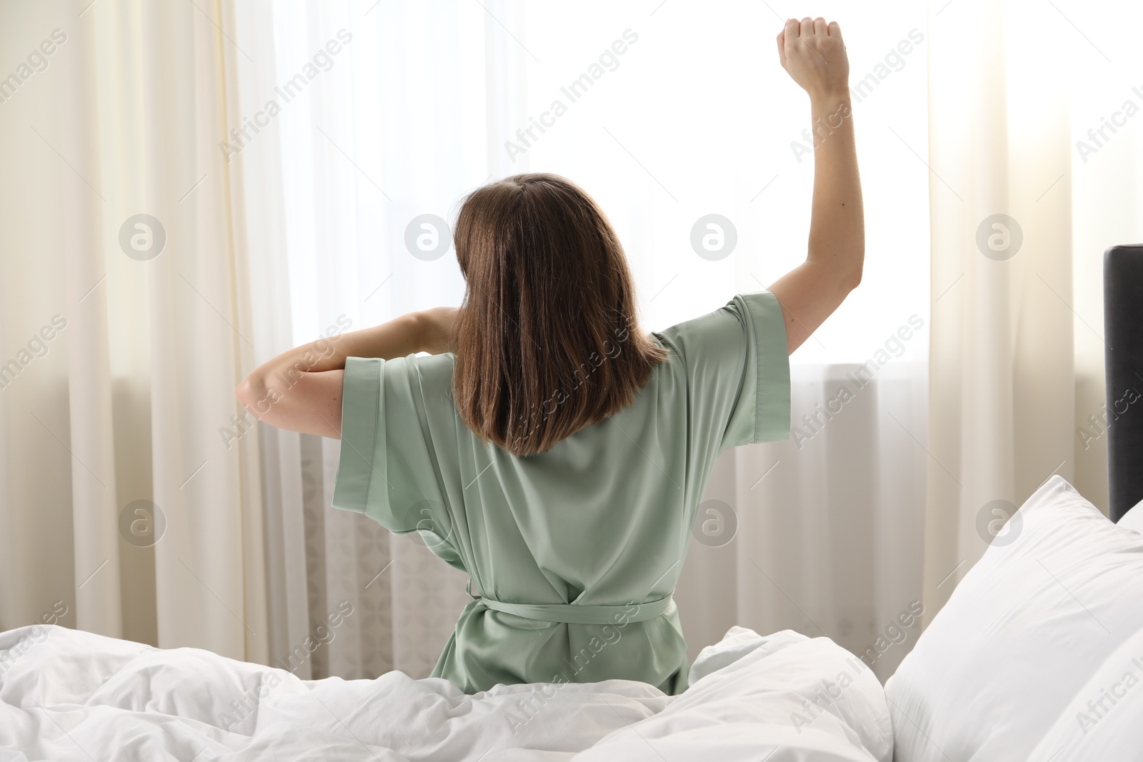 Woman stretching in bed at home, back view Photo of Woman stretching in bed at home, back view