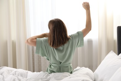 Photo of Woman stretching in bed at home, back view