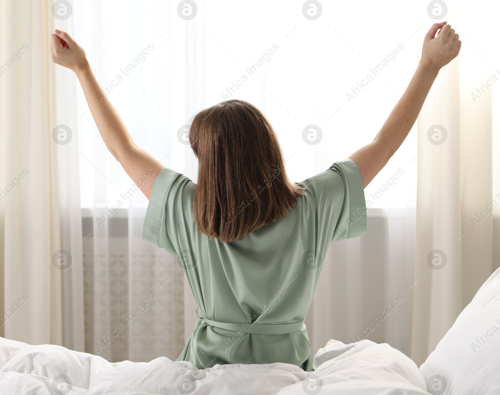Woman stretching in bed at home, back view Photo of Woman stretching in bed at home, back view