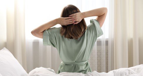 Photo of Woman stretching in bed at home, back view